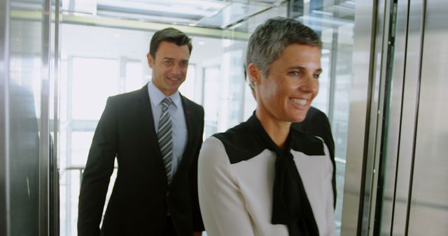 Smiling business people getting out of the elevator in office 4k