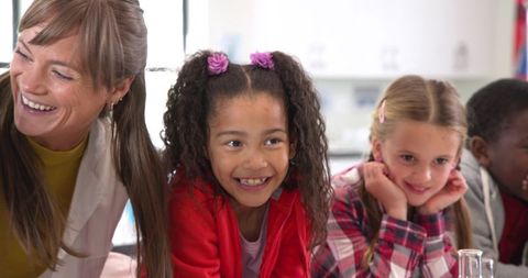 Cheerful Teacher Guiding Young Students in Classroom Science Experiment