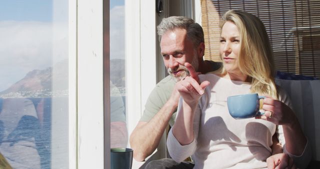 Happy Couple Enjoying Morning Coffee by Large Window with Ocean View - Download Free Stock Images Pikwizard.com