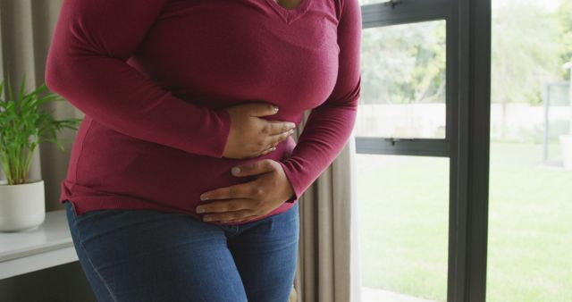 Image of midsection of plus size african american woman having stomach ache. health and spending time at home.