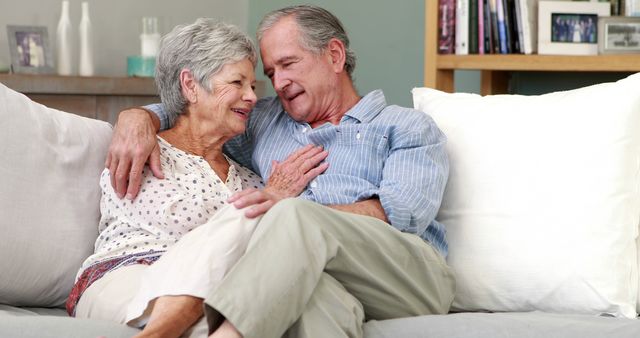 Seniors embracing on couch exuding love and companionship. Suitable for themes around aging gracefully, long-term marriage, emotional wellness, and family life. Useful for articles, senior lifestyle blogs, advertisement of retirement homes, or promoting senior health services.