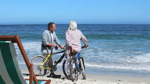 Senior Couple Enjoying Beachside Adventure with Bicycles