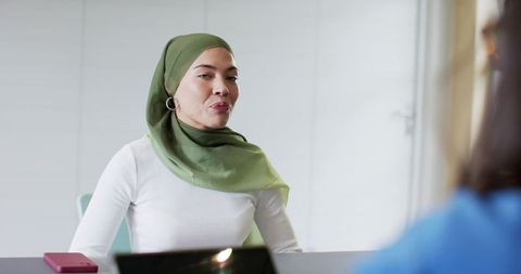 Confident muslim woman wearing green hijab speaking during professional office interview