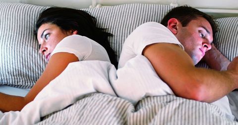 Couple distracted by technology in bed