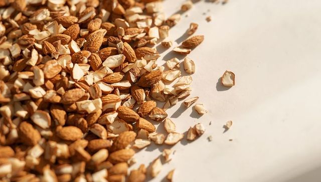 Scattered whole and chopped almonds on parchment closeup natural texture