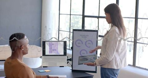 Businesswoman presenting interactive data dashboard to colleague in modern office meeting