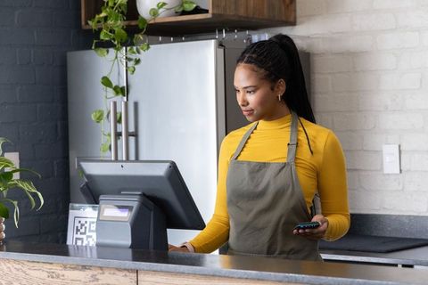 African-american barista processing mobile payment at modern cafe counter with qr code