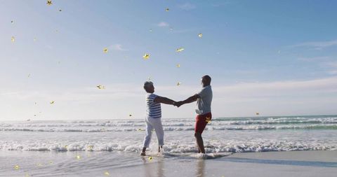 Senior Couple Holding Hands on Sunny Beach with Gold Stars Celebrating Love
