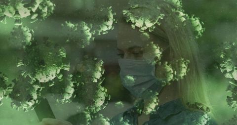 Masked woman using smartphone amid virus particle overlay