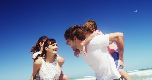 Joyful Family Piggyback Rides at the Beach on a Sunny Day - Download Free Stock Images Pikwizard.com