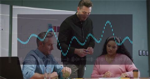 Presenter leaning over table explaining data visualization to colleagues in office meeting