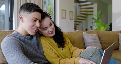 Couple Relaxing with Laptop on Couch in Modern Living Room