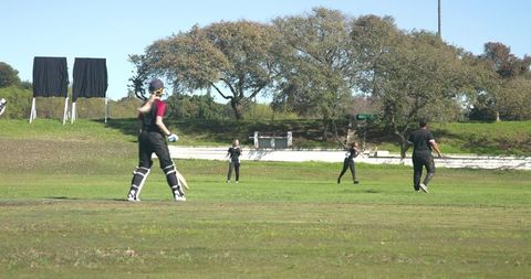 Diverse cricket players practicing on green field outdoors