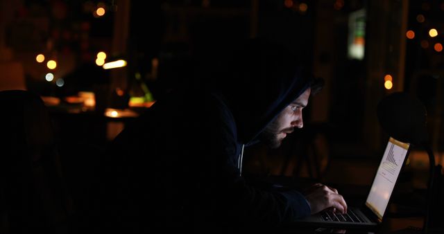 Hacker using laptop at night in the office