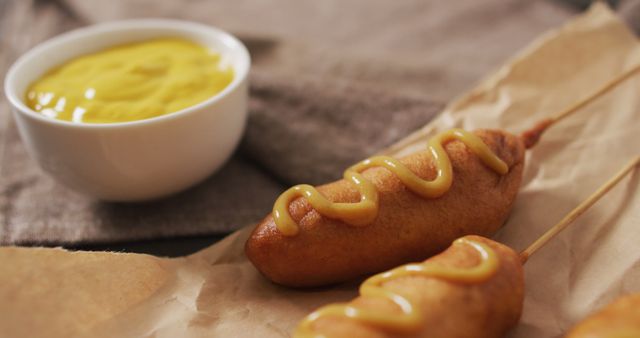 Corn dogs are garnished with mustard, next to a bowl of dipping mustard. Perfect for food blogs, fast food advertisements, restaurant menus, culinary magazines, and social media posts celebrating American cuisine. Ideal for illustrating quick meals and snack ideas.