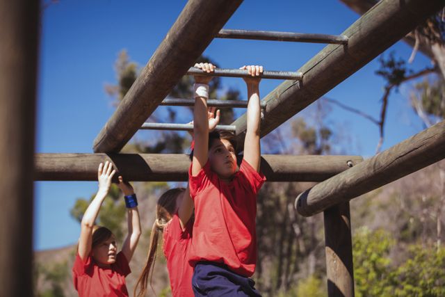 Kids climbing monkey bars during obstacle course training in the boot camp