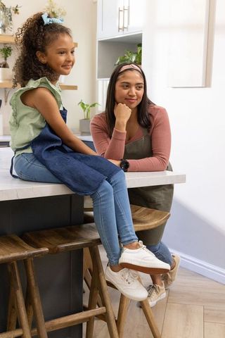Mother and african american preteen bonding on kitchen island, home cooking and learning