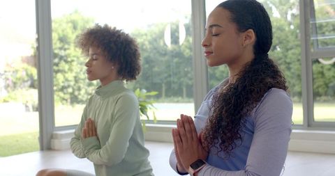 African women practicing meditation in sunlit yoga room for mindfulness and wellness