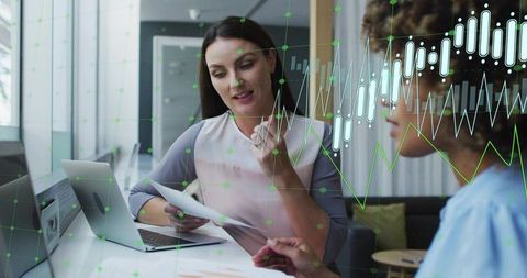 Businesswomen Analyzing Financial Data in Office with Digital Graph Overlay