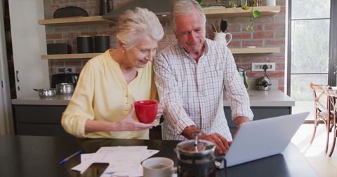 Senior Couple Enjoying Technology and Coffee in Modern Kitchen