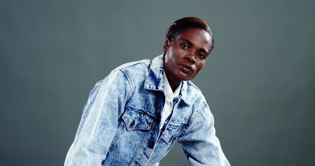 African American woman in casual denim attire leans forward, with copy space. Her expression is focused and determined, suggesting confidence and readiness for action.