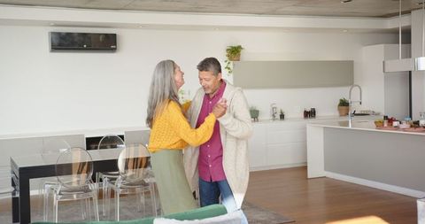Happy Senior Couple Dancing in Contemporary Kitchen