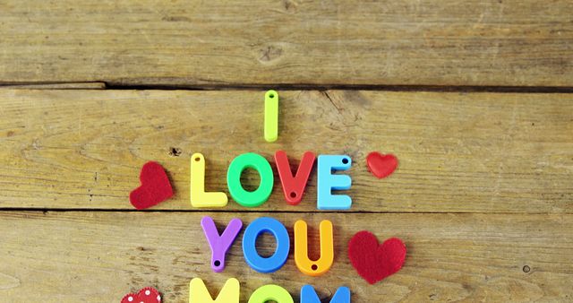 Colorful letters spell out I LOVE YOU on a wooden background, with red hearts accentuating the message, with copy space. It's a simple yet charming expression of affection, suitable for Valentine's Day or romantic occasions.