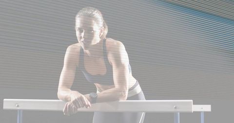 Female athlete leaning on rail in studio training with dramatic streak lighting