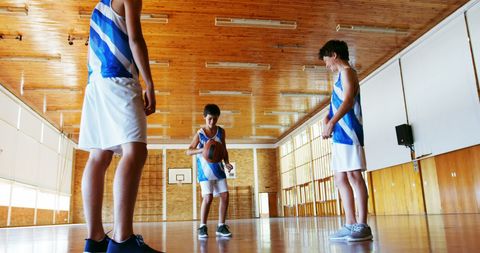 Boys practicing basketball dribbling in gym with determination
