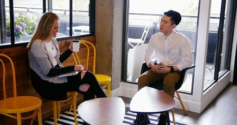 Professional Colleagues Engaging in Discussion Near Office Window