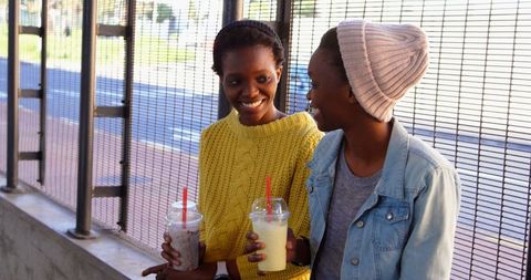 Twin Sisters Enjoying Smoothies and Conversation Outdoors
