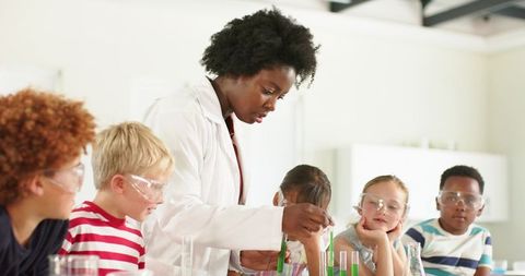African american teacher guiding students through hands-on chemistry experiment with test tubes