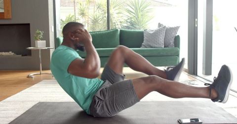 Man performing bicycle crunch on exercise mat in living room