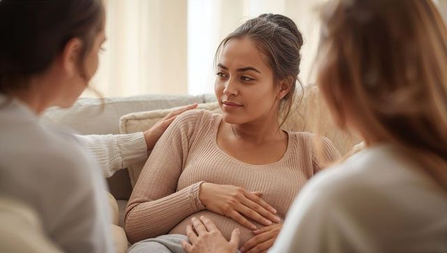 Expectant woman resting hands on pregnancy belly while receiving comforting maternity support