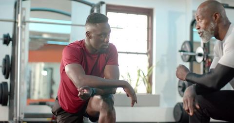 African american coach mentoring athlete during strength training in sunlit gym studio