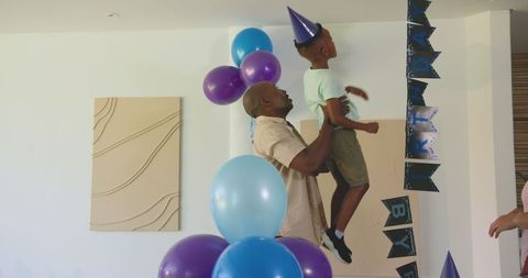 Father Lifting Son to Decorate for Birthday Celebration
