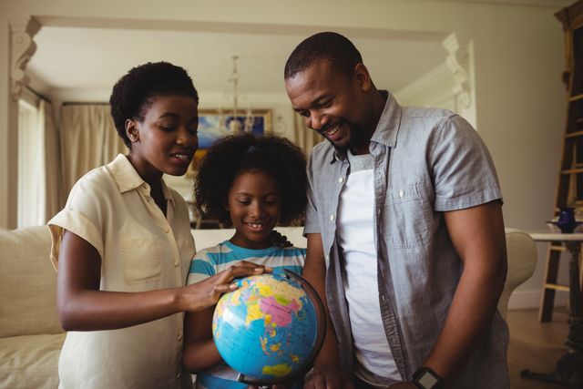 Family exploring globe together in living room. Perfect for educational content, family bonding themes, parenting articles, and multicultural family representations.