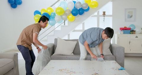 Duo Preparing Living Room for Upcoming Celebration with Balloons