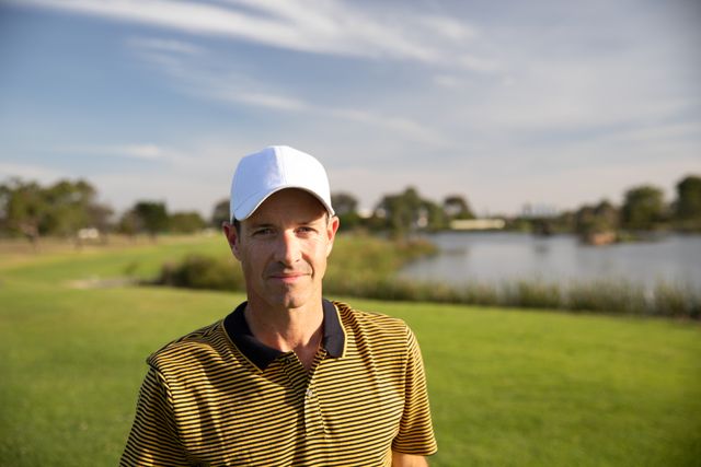 Portrait of Caucasian male golfer practicing on a golf course on a sunny day wearing a cap and golf clothes. Hobby healthy lifestyle leisure.