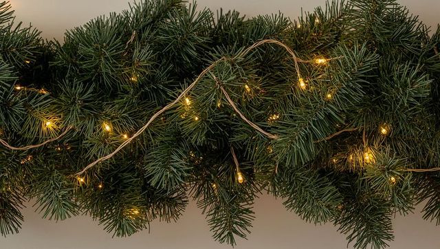 Glowing evergreen garland running along mantel with warm white string lights