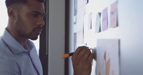 Businessman Writing on Memo Board in Modern Office Setting