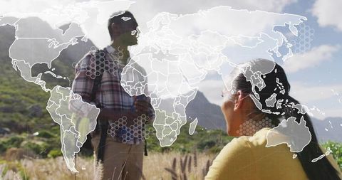 Couple hiking in mountain meadow with world map and digital network overlay