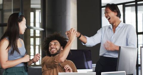Diverse team celebrating success enthusiastically in modern office