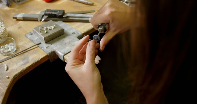A jeweler is crafting a piece of jewelry at a workbench, with copy space. Precision and attention to detail are evident in the artisan's hands as they work on the intricate design.