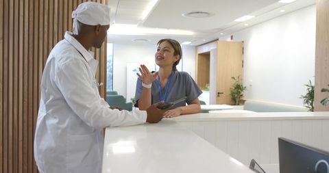 Medical staff consulting at modern clinic reception desk with tablet and warm collaboration