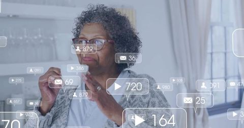 Senior woman viewing social media notifications at home holding mug with overlay icons