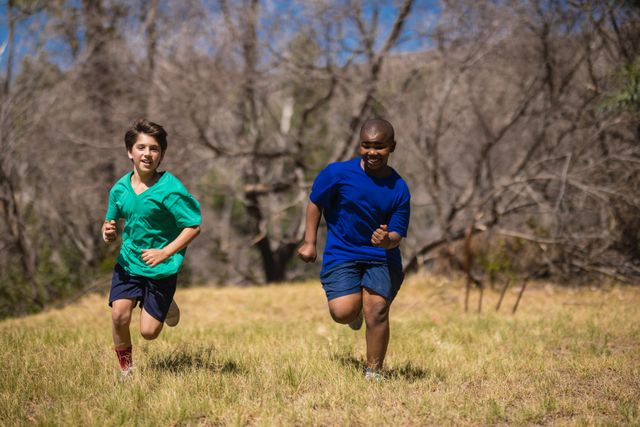 Two boys running on grass during an obstacle course in a boot camp. They are enjoying an outdoor activity that promotes fitness, teamwork, and a healthy lifestyle. Ideal for use in advertisements for children's fitness programs, outdoor adventure camps, or educational materials promoting physical activity.