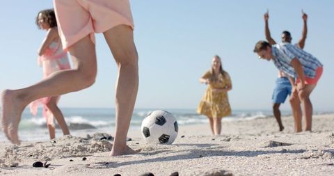 Friends Playing Soccer on Sandy Beach Under Clear Sky