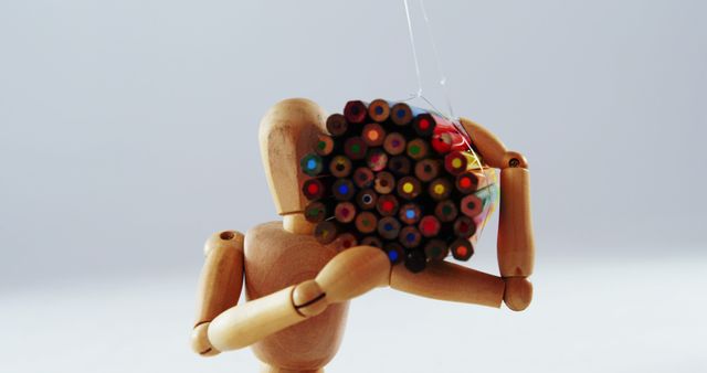 Wooden mannequin holding stack of colorful pencils - Download Free Stock Images Pikwizard.com