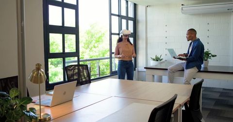 Colleagues testing virtual reality headset in bright modern office collaborative workspace